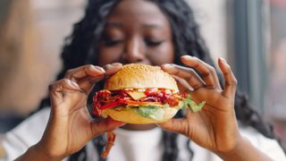 A woman holds up a hamburger