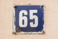 the number 65 on a metal plate against a peach background