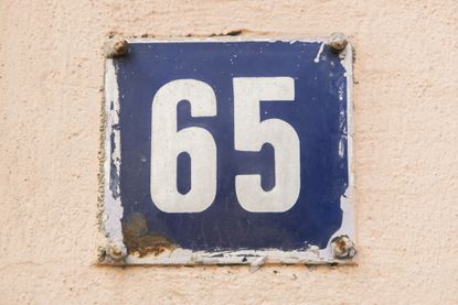 the number 65 on a metal plate against a peach background