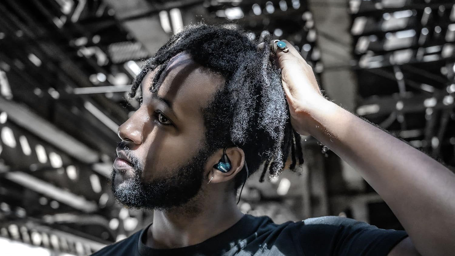 Man pulling his hair aside to reveal Shure SE215 Pro in his ears