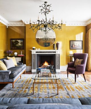 Living room ceiling light ideas with a large black chandelier with natural motifs hanging in a yellow room