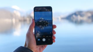 Honor Magic7 Pro phone held in a hand showing the camera UI with a castle in the middle of a lake