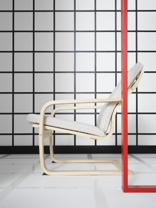 A room with a black and white chequered wall and an all-white recliner chair in side profile