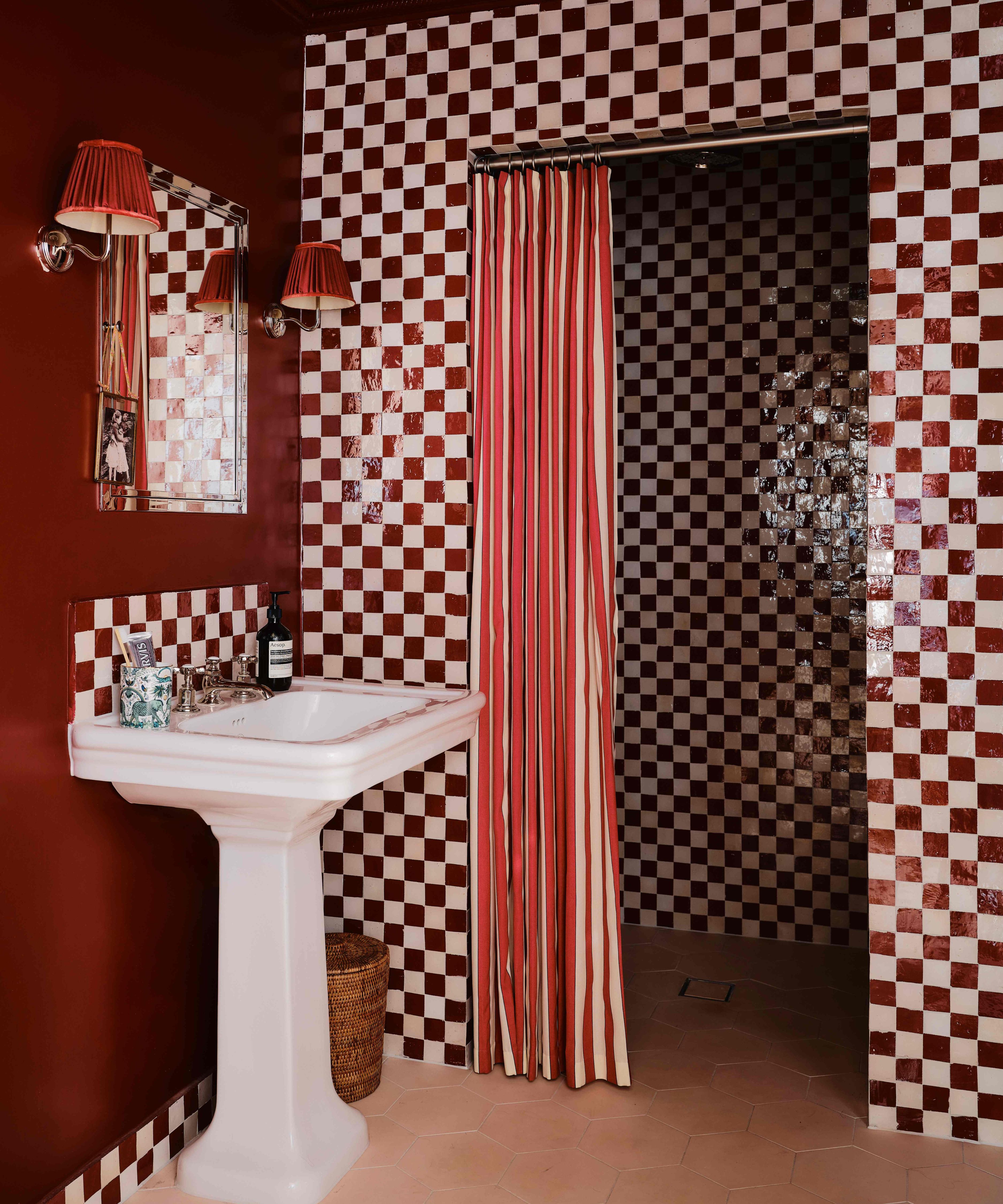 small powder with dark red painted walls and a red and white checkerboard shower enclosure with a shower curtain