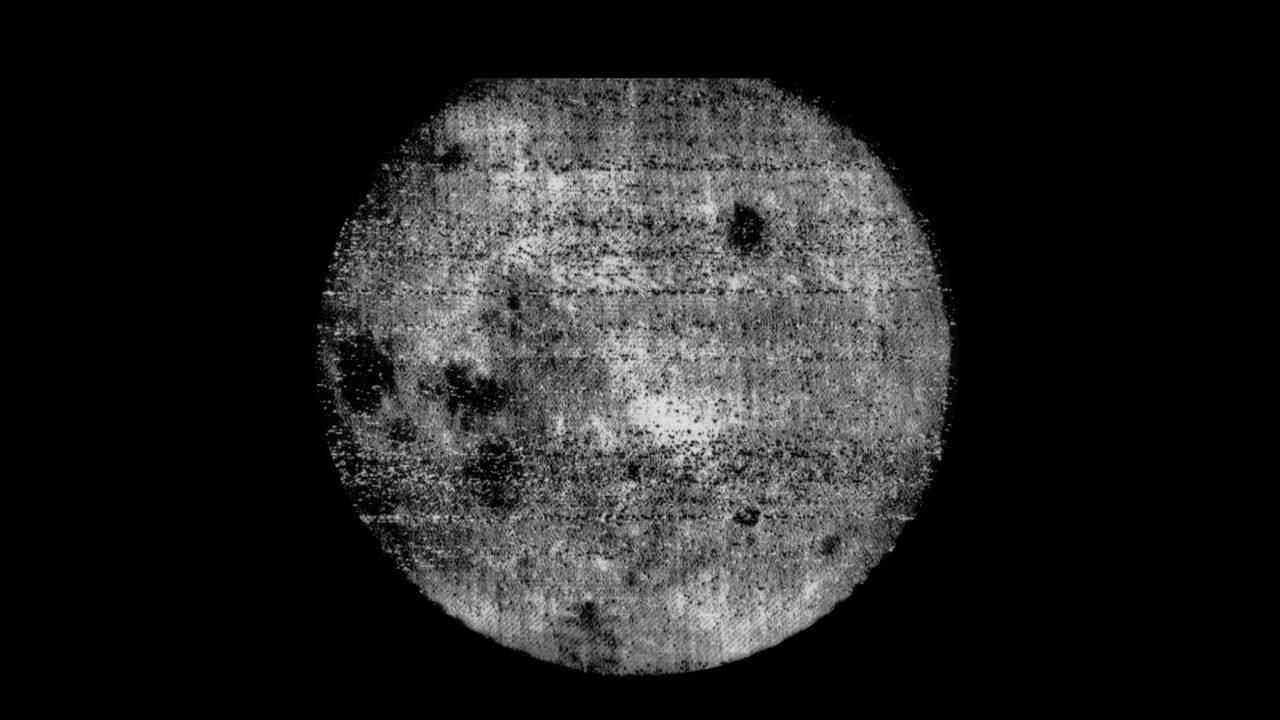 A gray sphere with various dark dots is seen against a black background