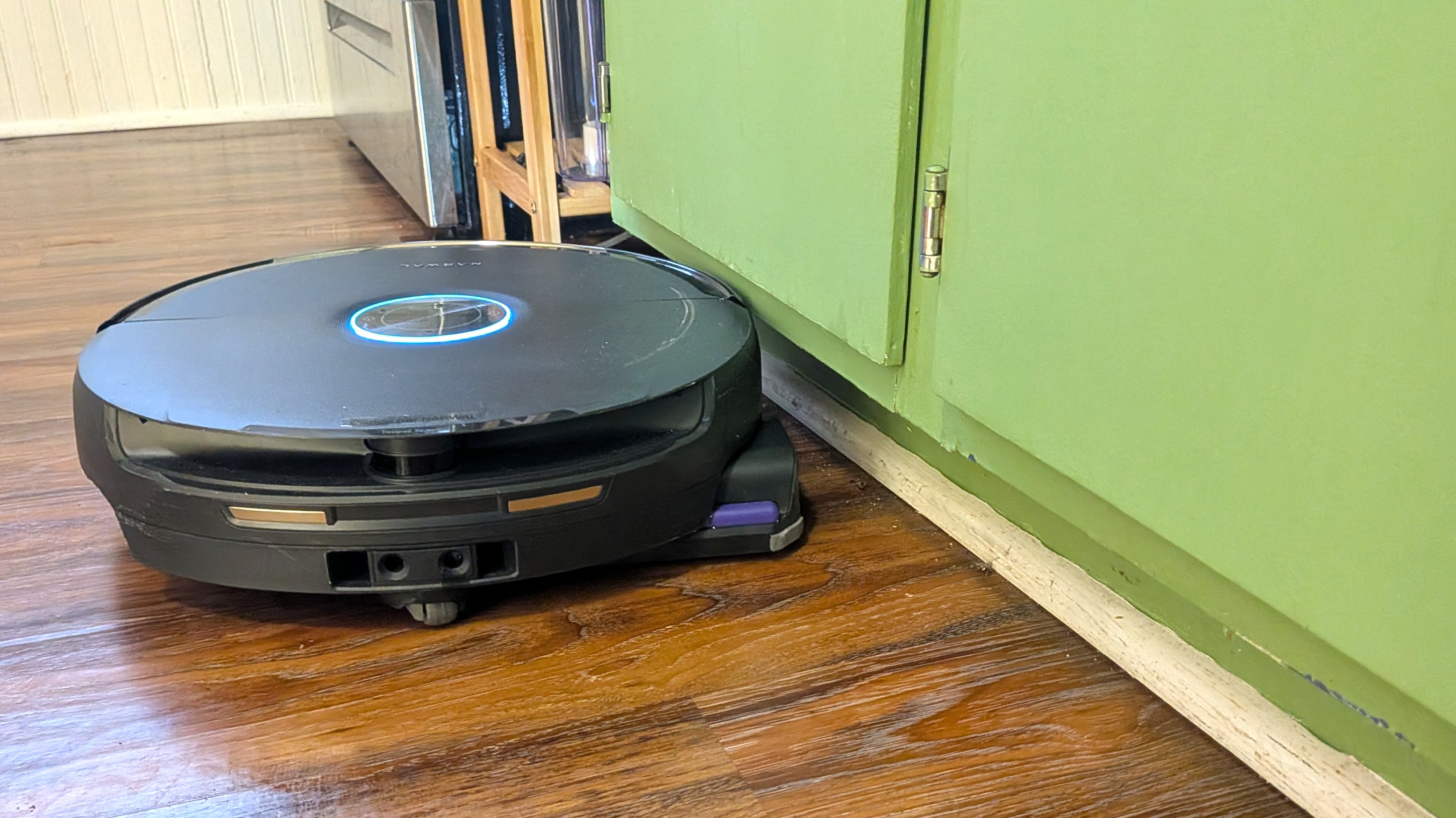 Narwal Flow 2 robot vacuum cleaning edge of room beside cabinet