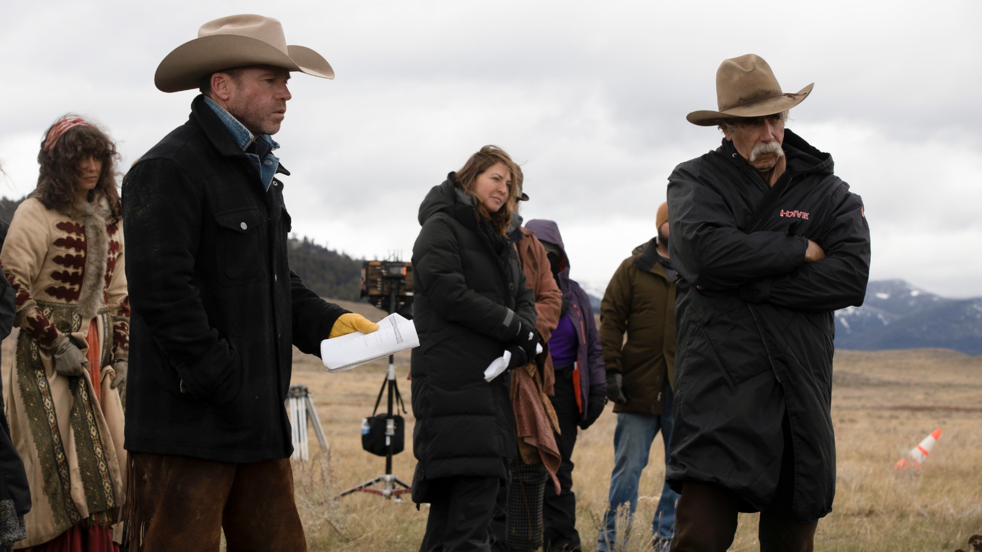 Taylor Sheridan holding paper and Sam Elliott crossing his arms behind the scenes of 1883.