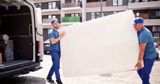 Two delivery men collect an old mattress as part of a White Glove Delivery service