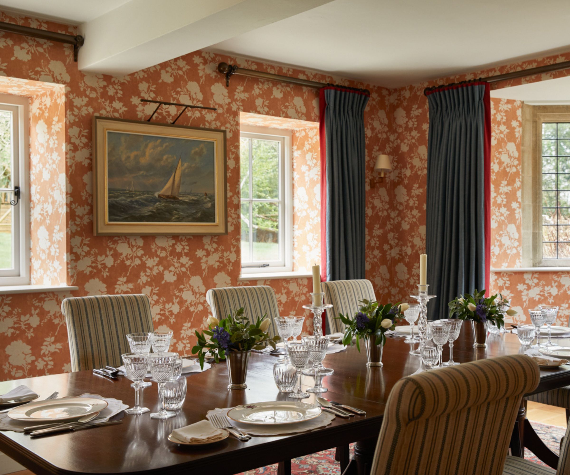 A large dining room with floral wallpaper and antique art