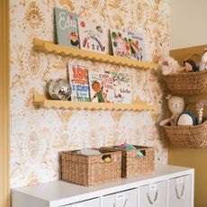 A children's room with IKEA MOSSLANDA picture ledges displaying books, adorned with a wavy trim and painted yellow