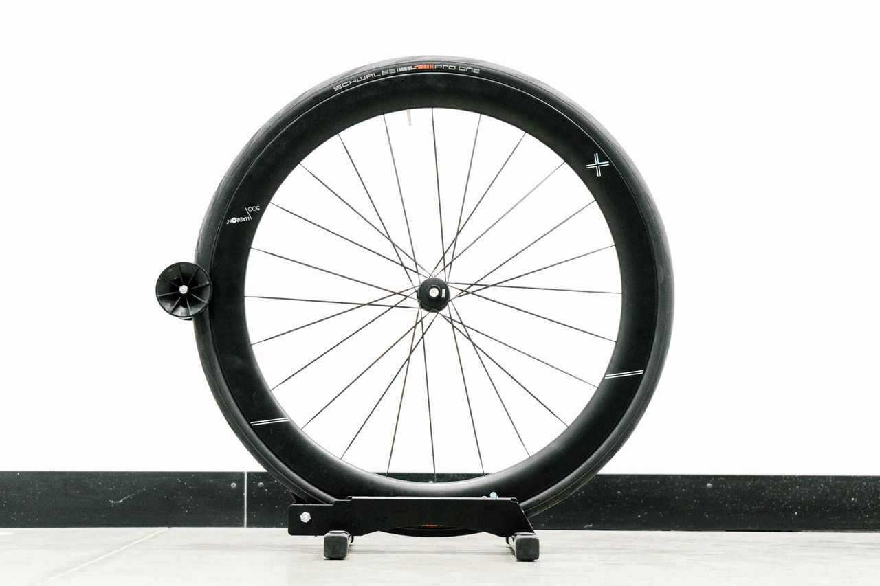 An aero road wheel stands against a white wall