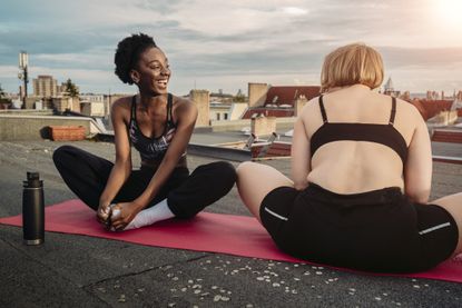 Smiling female friends exercising on rooftop, morning yoga, best time to do yoga