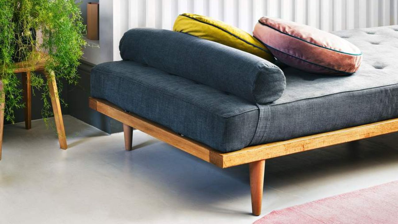 White wood panelled and brick wall, chaise longue and polished concrete floor