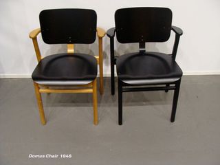 two chairs photographed against a white wall and grey floor. Left chair is black and brown, right chair is all black