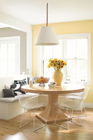 yellow dining room with wooden table and white wire chairs