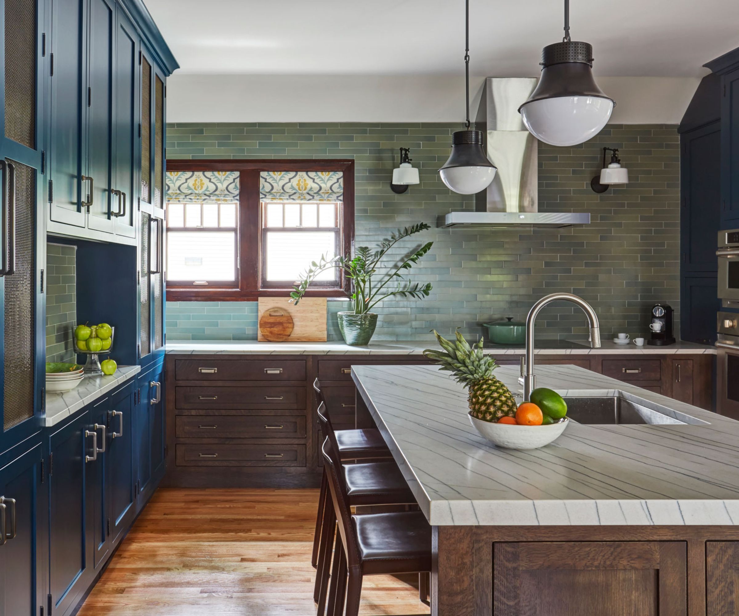 A Craftsman kitchen with blue cabinets, a wooden island, and green wall tiles