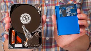 A man holding an SSD and a hard drive