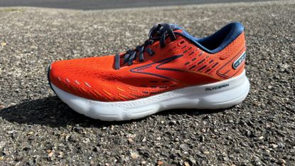 The Brooks Glycerin 20 shoe in orange on a sidewalk