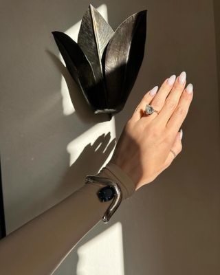 Woman's hand in the light while wearing tilted large pear-shaped engagement ring.