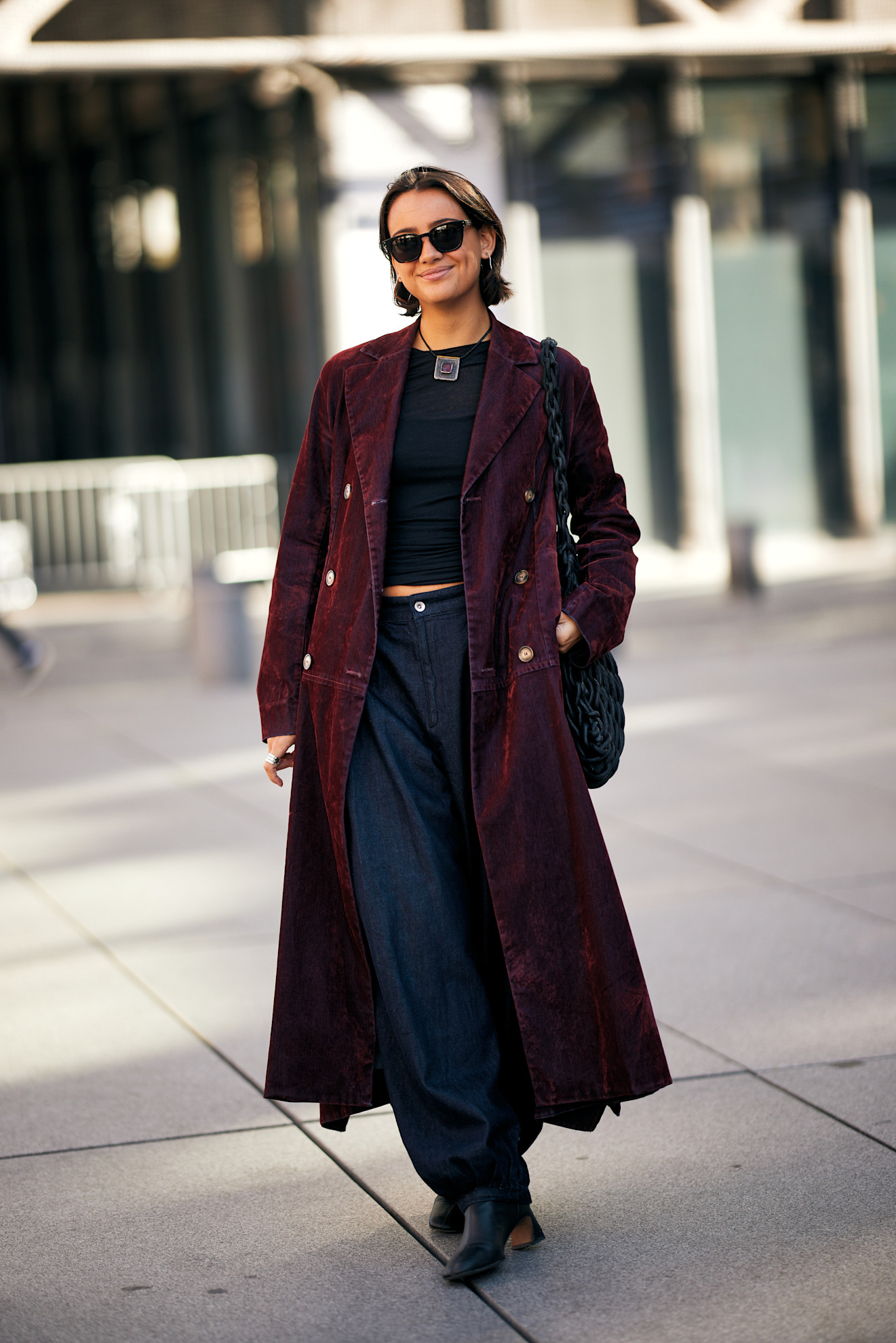 Woman in long red jacket, balloon jeans, and black leather heeled boots.