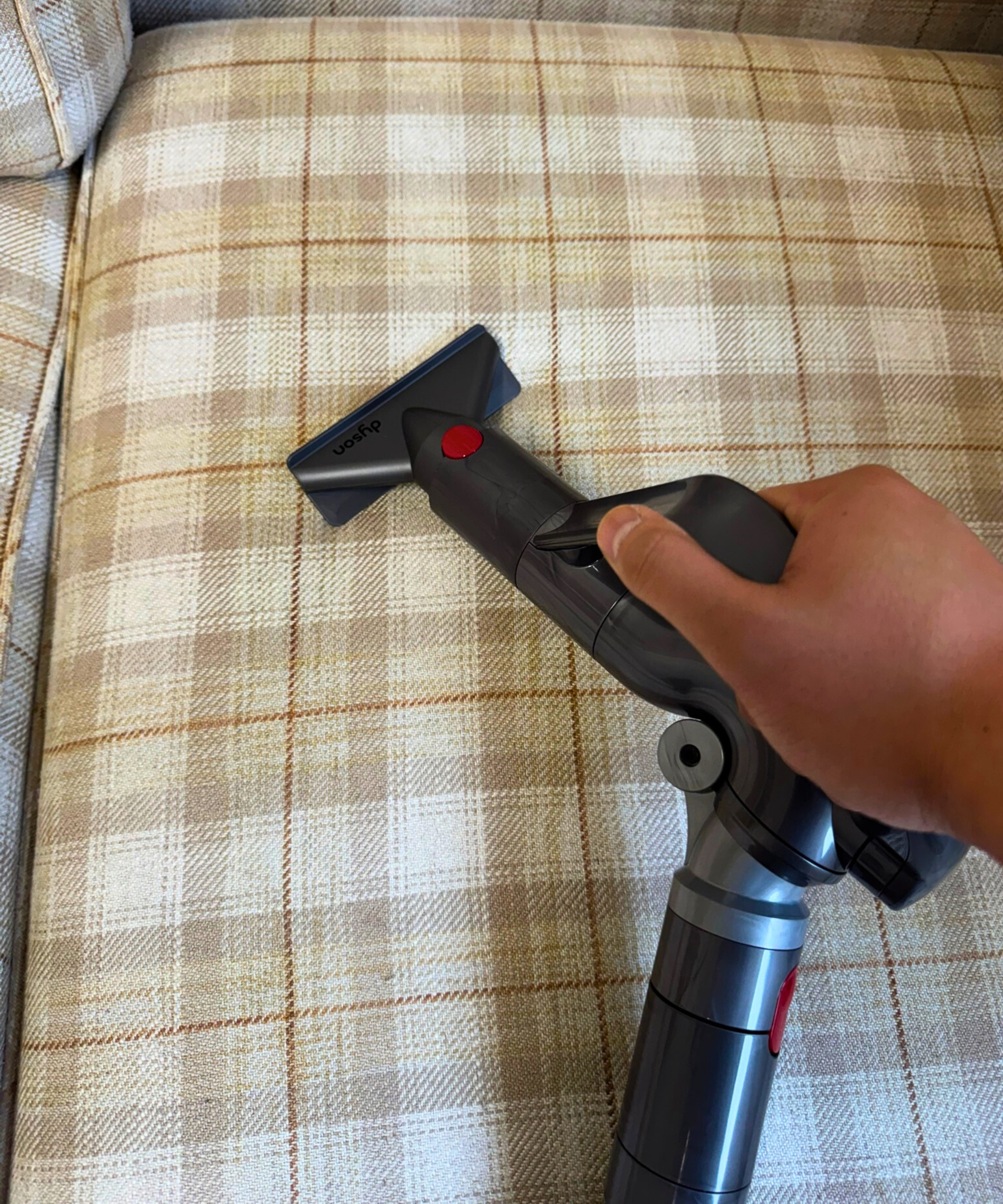 Hand holding the Dyson Big Ball Turbinehead upholstery tool on beige sofa in Bristol ARC.