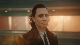 Image from the Marvel T.V. show Loki, season 2 episode 6. Close up of a man with dark slicked back hair who looks sad but determinedly into the distance. He is wearing a dark jacket, light shirt and black tie.