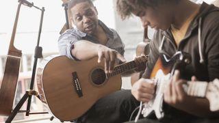 Man teaching a student how to play the guitar