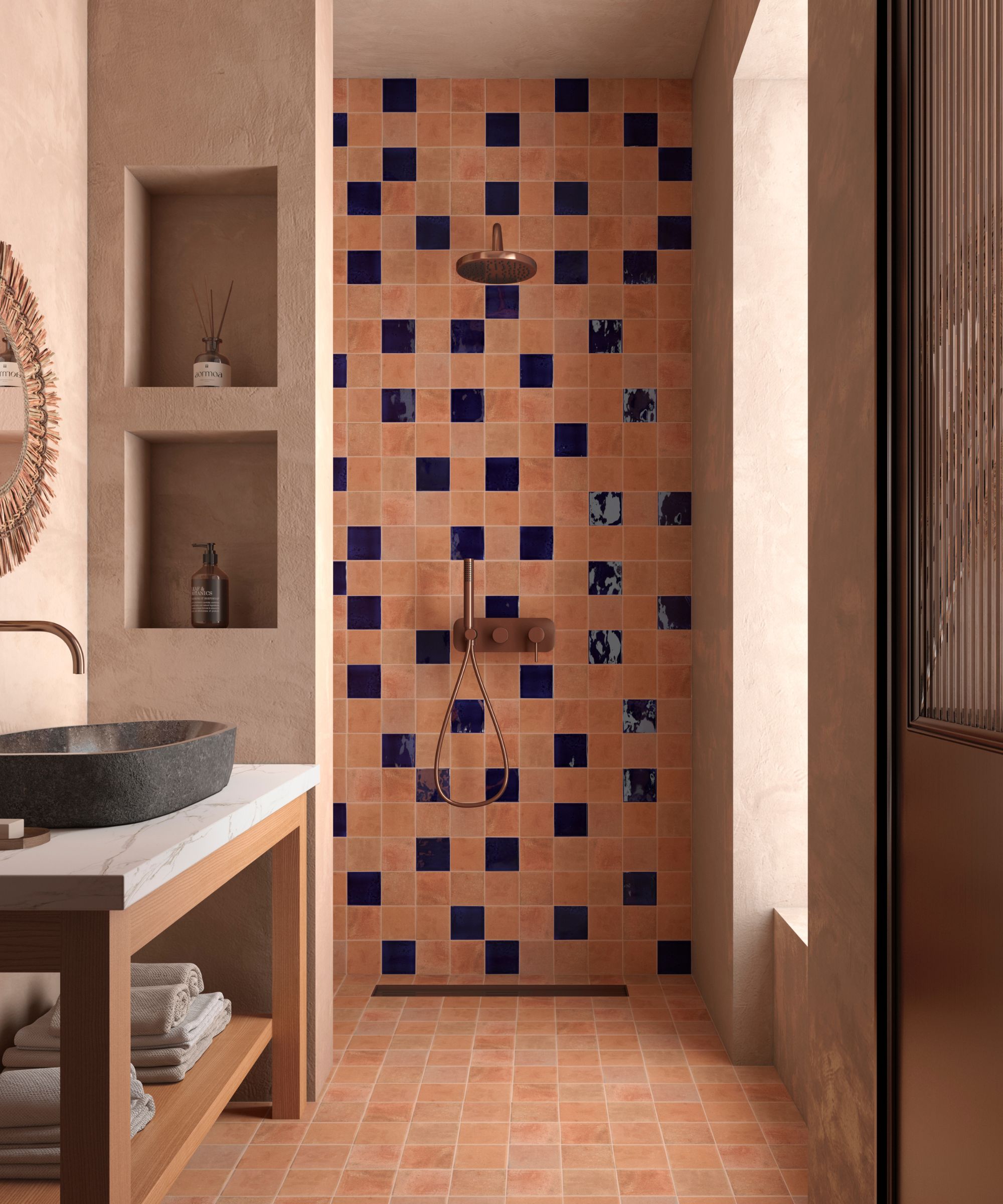 A walk-in shower with terracotta square tiles randomly punctuated by cobalt blue glazed tiles, a stone basin on a marble and wood vanity, and plastered walls with built-in niches.