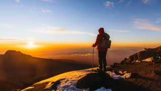 Man hiker achieved the dream enjoying the awe sunrise from the top of Kilimanjaro mountain