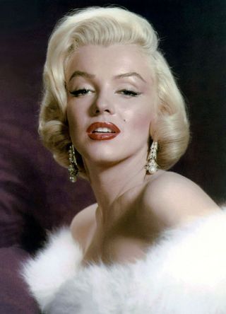 Marilyn Monroe wearing pearl earrings and white fur wrap