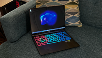 A gaming laptop, open, and perched on a couch.