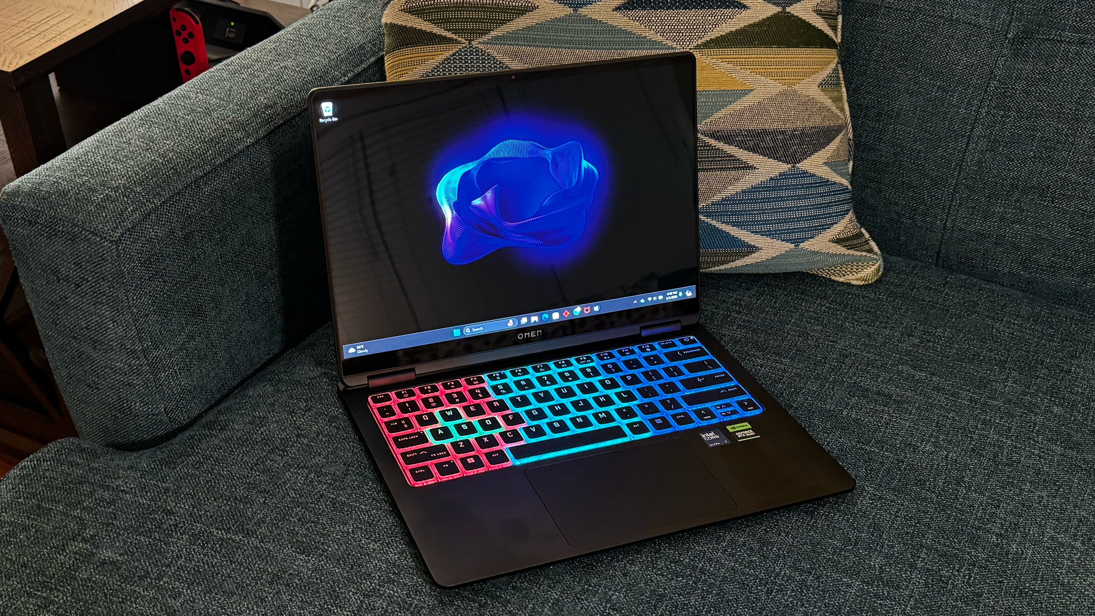 A gaming laptop, open, and perched on a couch.