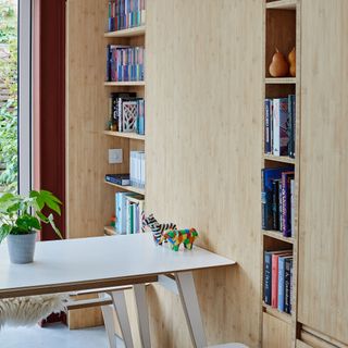 detail of a dining table beside a large timber storage unit with shelving and cupboards