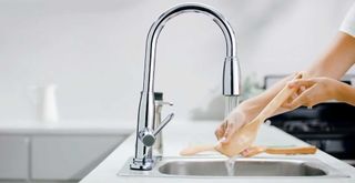 woman rinsing a wooden spoon under a tap to show step two of how to clean wooden spoons properly
