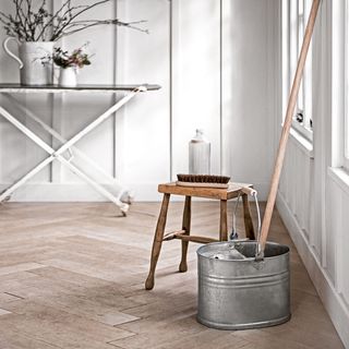 room with wooden table mop bucket and white walls