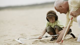 Check out our Cyber Monday deals on metal detectors. Shown here, a father and son on the beach with metal detectors.