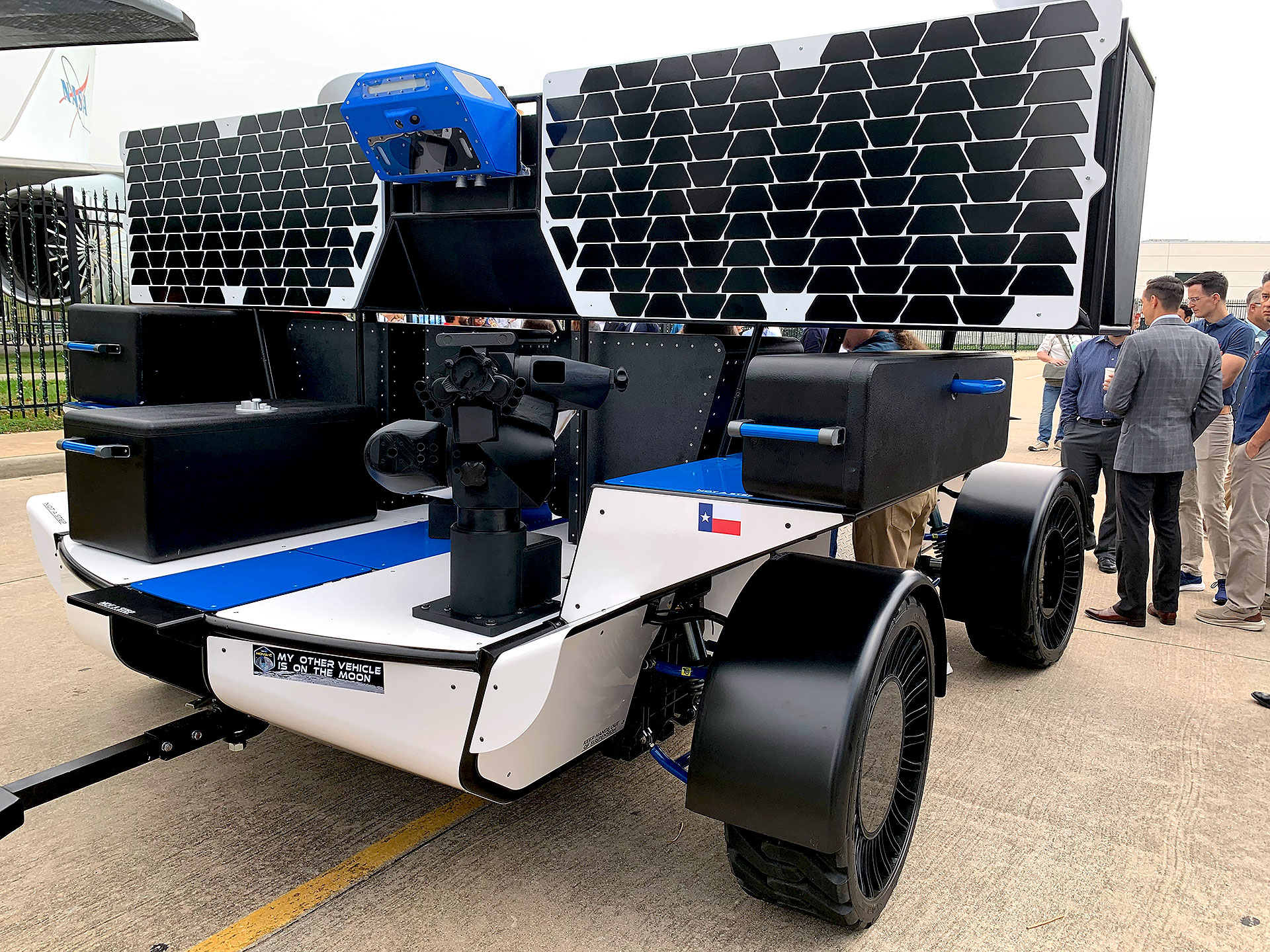 a six-wheeled blue and white moon rover prototype, seen here on earth from the rear