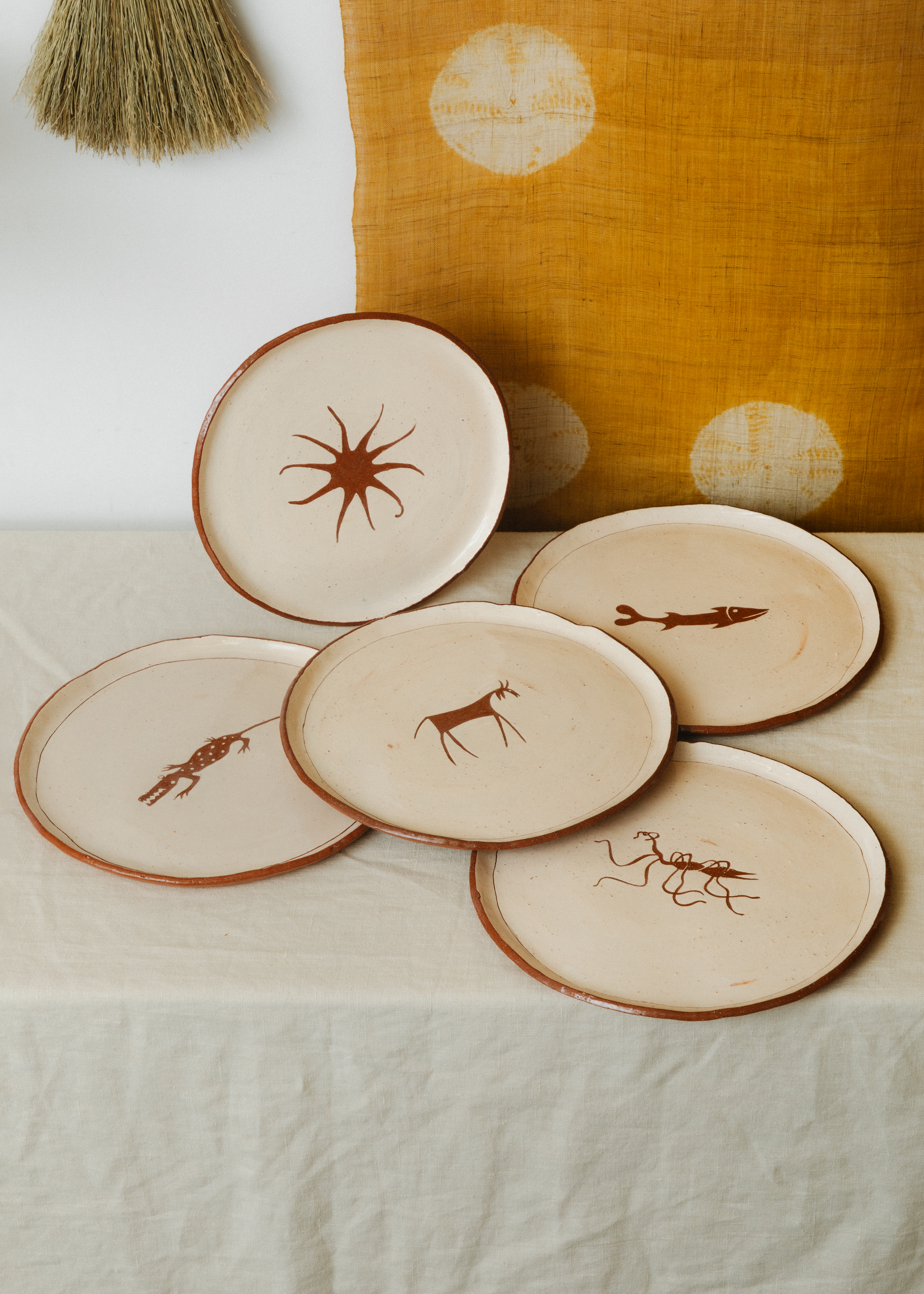 A series of beige ceramic plate with animalesque silhouettes at their center.