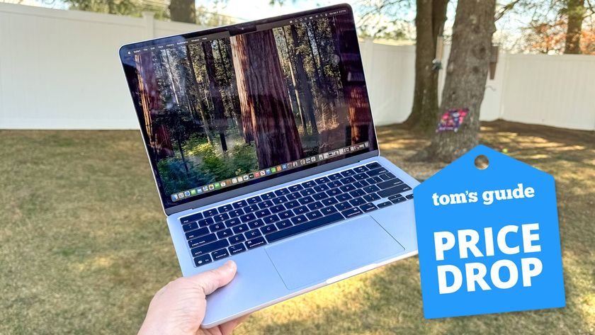 MacBook Air M4 being held in hand in garden with Tom&#039;s Guide Price Drop badge