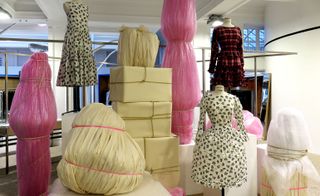 Art installation featuring clothes on mannequins and sculptures wrapped in recycled paper