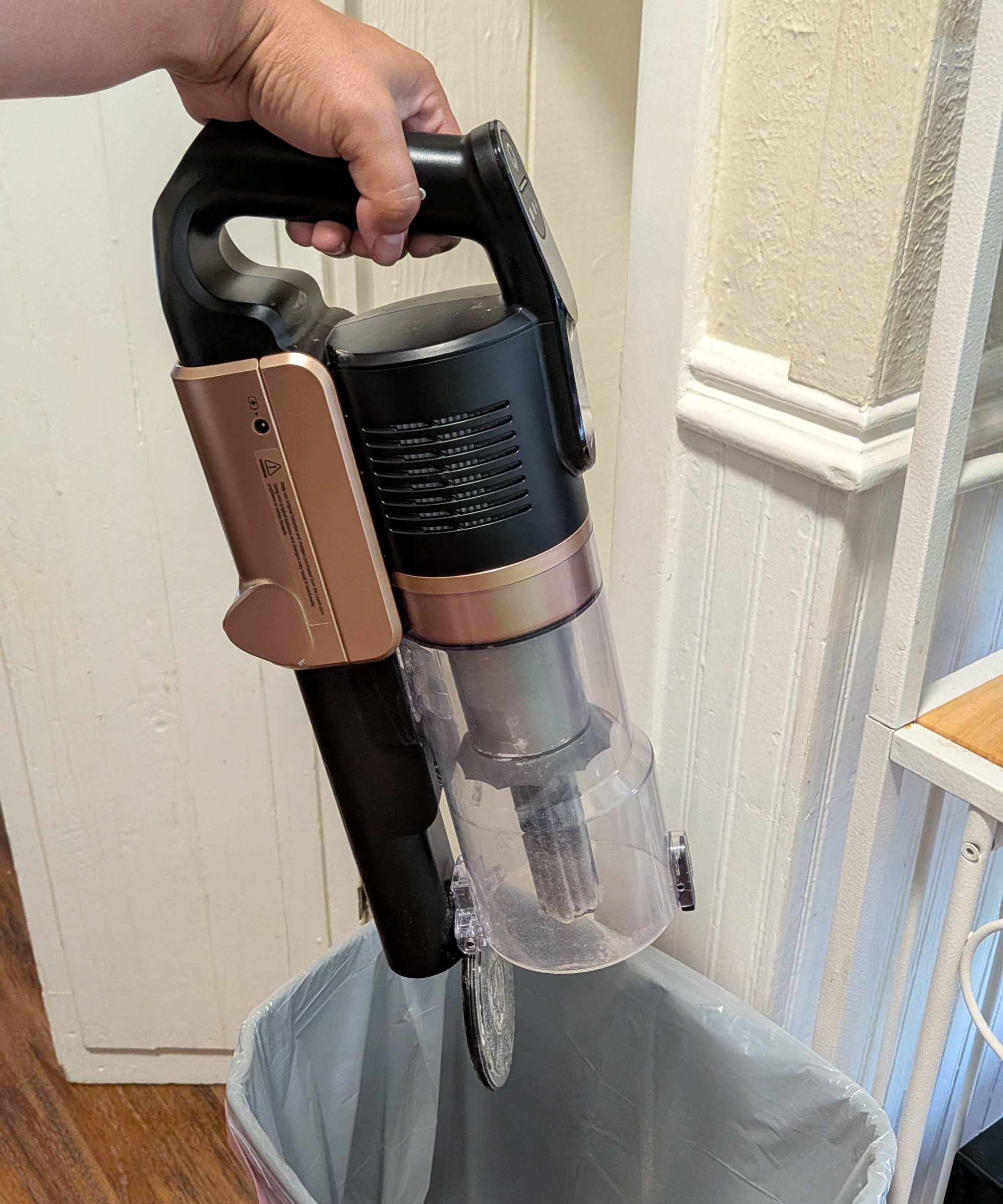 Dumping the dustbin of the Levoit VortexIQ Pro vacuum cleaner over a trashcan.