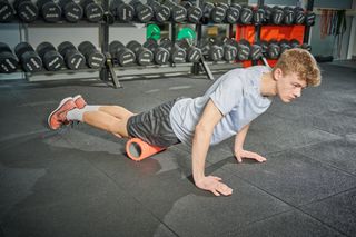 Male cyclist foam rolling his quads to reduce knee pain from cycling