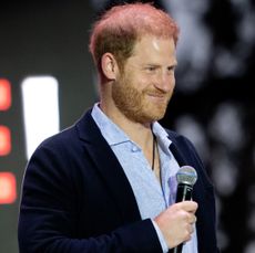 Prince Harry holding a mic on stage