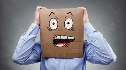 Man with a box on his head painted with a worried face.