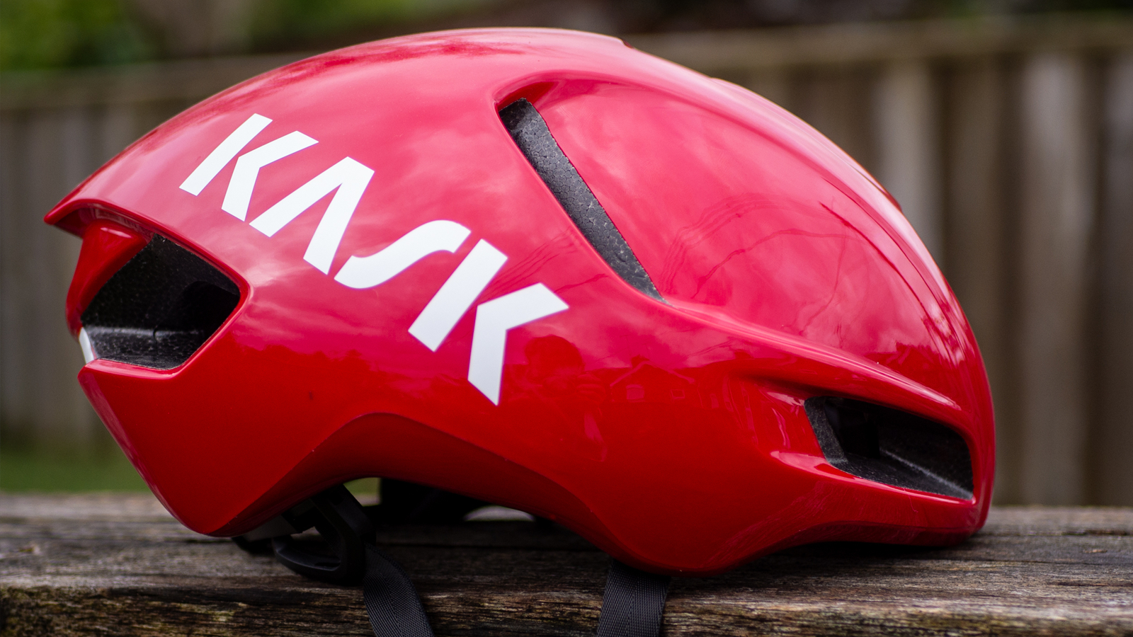 A red Kask Utopia Y aero helmet sits on a wooden bench