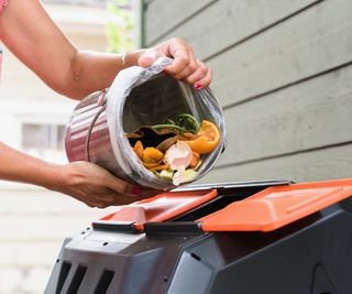 Filling a compost tumbler with food scraps