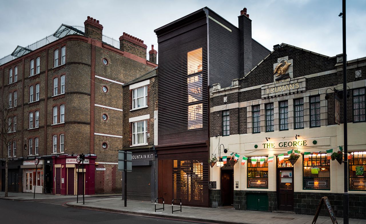 Exterior view of the building sandwiched between a shop (Mountain Kit) and a pub (The George), photographed during the day from across the street