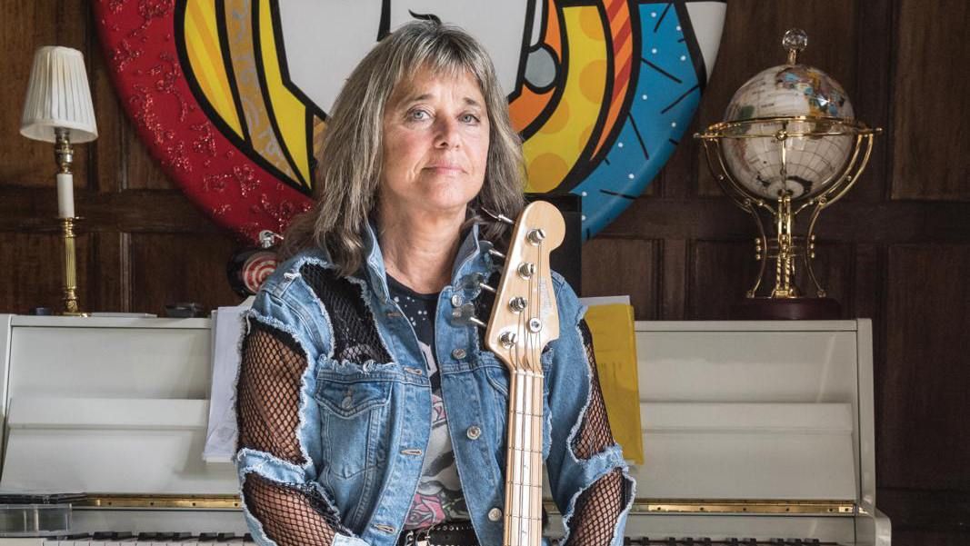 Suzi Quatro seated, holding a bass guitar