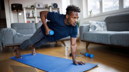 A man performing a renegade row with a dumbbell as part of a home workout 