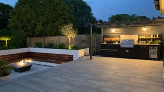 sunken garden at night with outdoor kitchen and built in seating